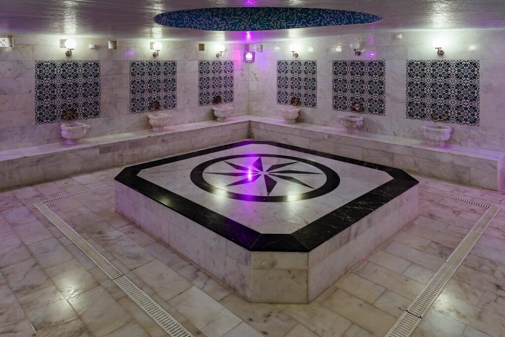 The marble hammam room at Old Hammam & Spa, with the heated central platform and marble basins set into mosaic-tiled walls