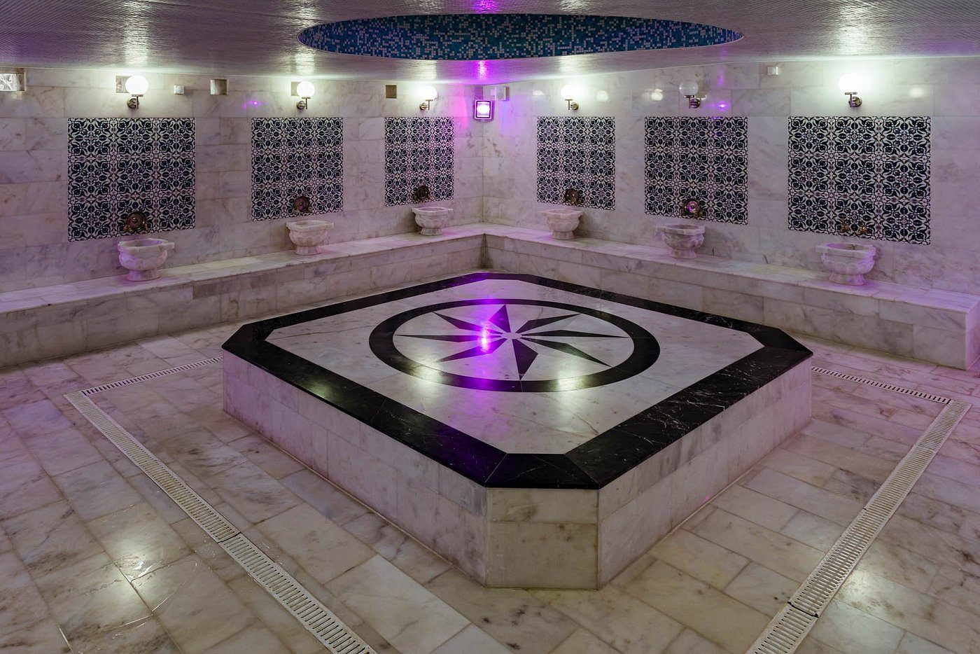 The marble hammam room at Old Hammam & Spa, with the heated central platform and marble basins set into mosaic-tiled walls
