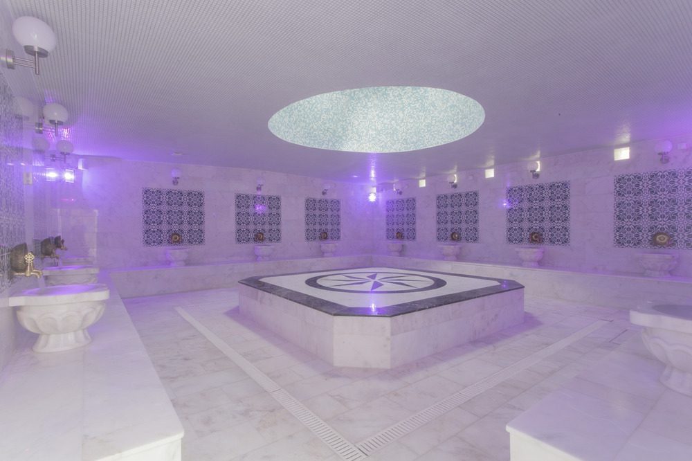 The tiled steam room at Old Hammam & Spa, with mosaic benches and a marble water basin