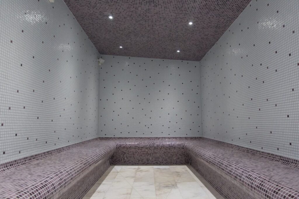 The tiled steam room at Old Hammam & Spa, with mosaic benches and a marble floor